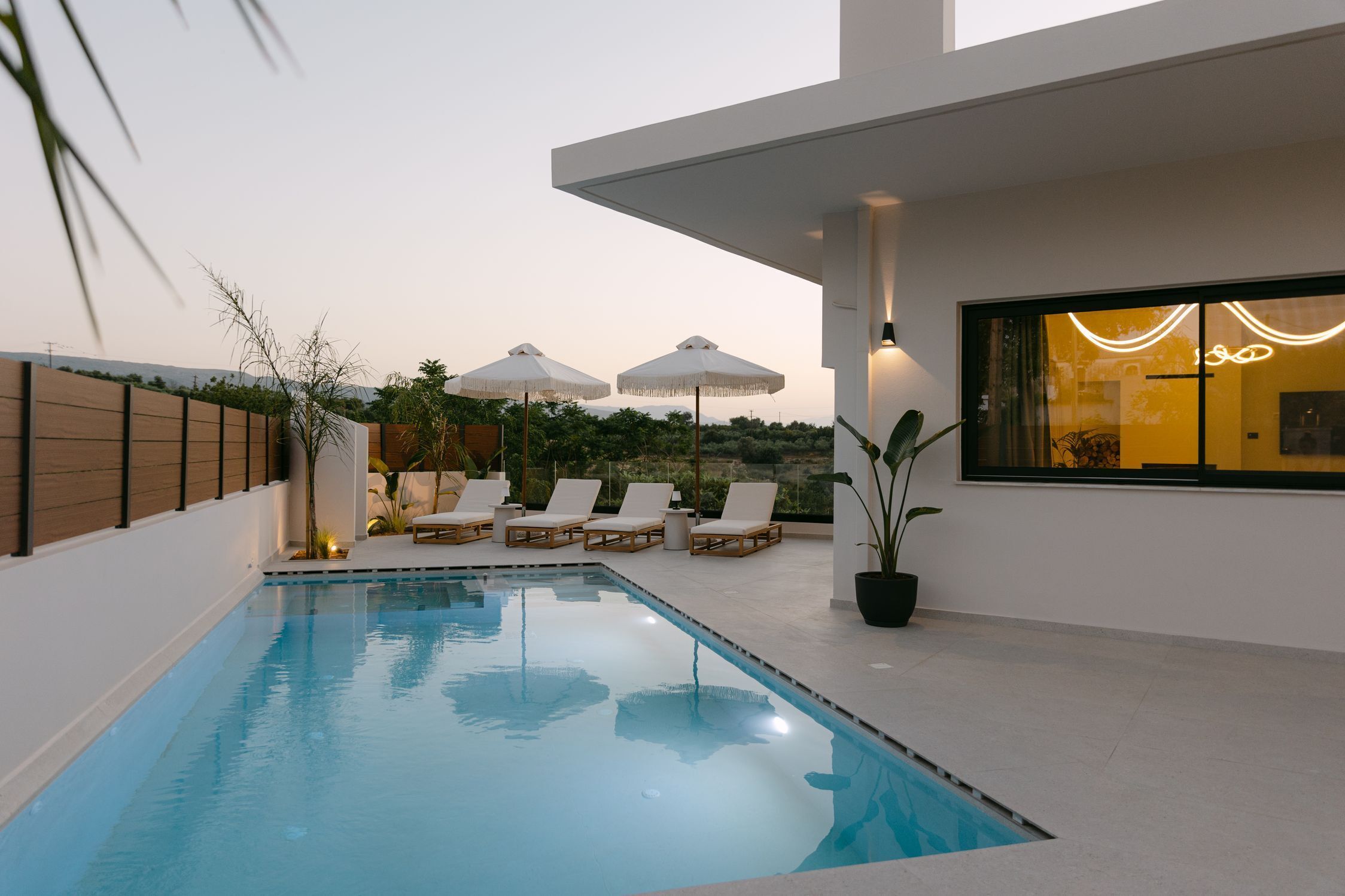 Uma área moderna com piscina ao ar livre, espreguiçadeiras e guarda-sóis.