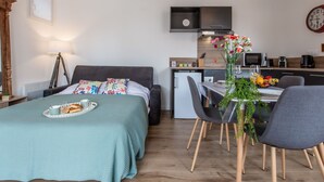 A compact living space with a bed, a dining table with chairs, a kitchenette, and a small kitchen area. - Cap Océan by Interhome (Capbreton)
