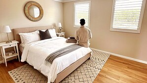 A bedroom with a bed, bedside tables, a mirror, and a ceiling light.