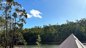 A tent set up on a sandy beach with a lake and trees in the background.