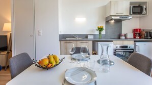 A modern kitchen with a dining area, including a table set with plates, cutlery, and a fruit bowl. - Cap Océan by Interhome (Capbreton)