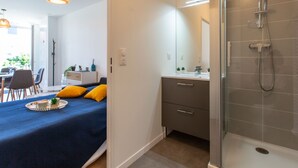 A modern bedroom with a bed, bedside table, and a shower area. - Cap Océan by Interhome (Capbreton)