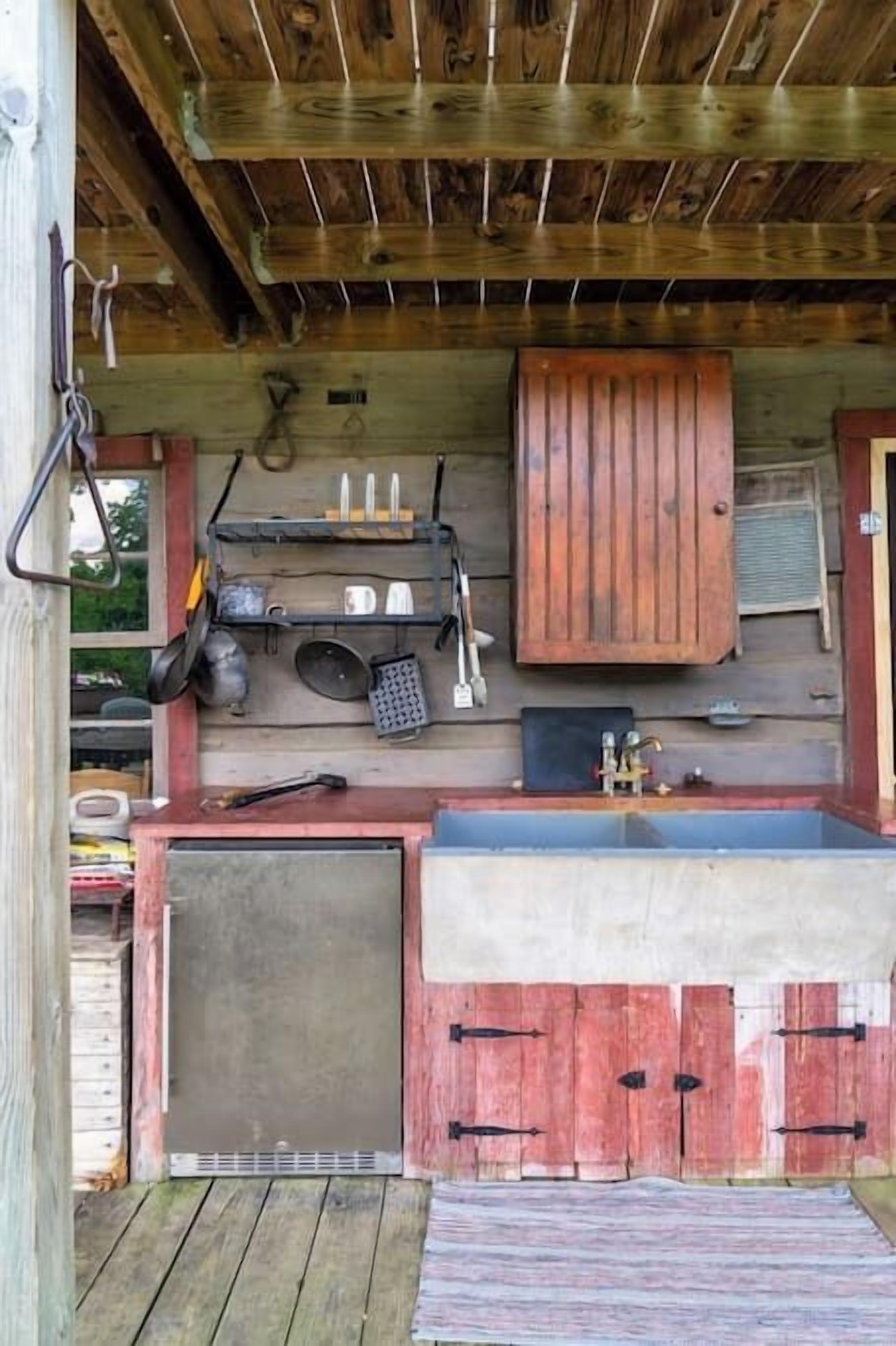 A rustic wooden cabin with a kitchen area featuring a sink, cabinets, and various kitchen utensils.