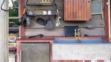 A rustic wooden cabin with a kitchen area featuring a sink, cabinets, and various kitchen utensils.