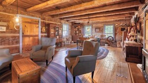 A rustic wooden interior with a cozy seating area, wooden floors, and a fireplace. - Vintage 1850's Log Cabin Glamping (Flora)