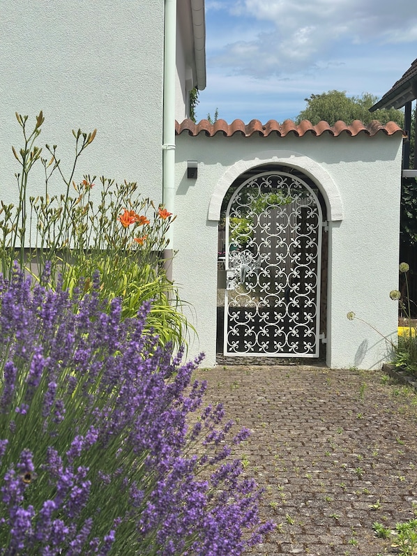 A building with a white exterior, a tiled roof, a brick pathway, and a decorative metal gate. - Cozy vacation apartment on the Rhine promenade. Family and group friendly! (Kehl)