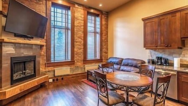 A spacious living area with a fireplace, a television mounted on the wall, and a dining table with chairs.