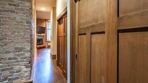 A hallway with wooden doors and a brick wall.