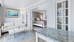 Un soggiorno moderno con un divano bianco, un tavolino in marmo e un quadro appeso al muro.