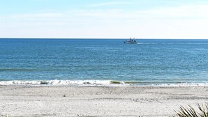 Una spiaggia con una barca all'orizzonte e cielo sereno.