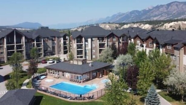 A resort with multiple buildings, a swimming pool, and mountains in the background.
