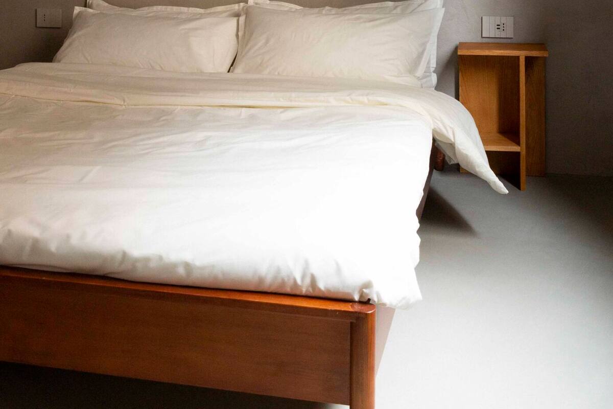 Ein Schlafzimmer mit einem hölzernen Bett, weißer Bettwäsche und zwei Nachttischen mit Wandlampen.