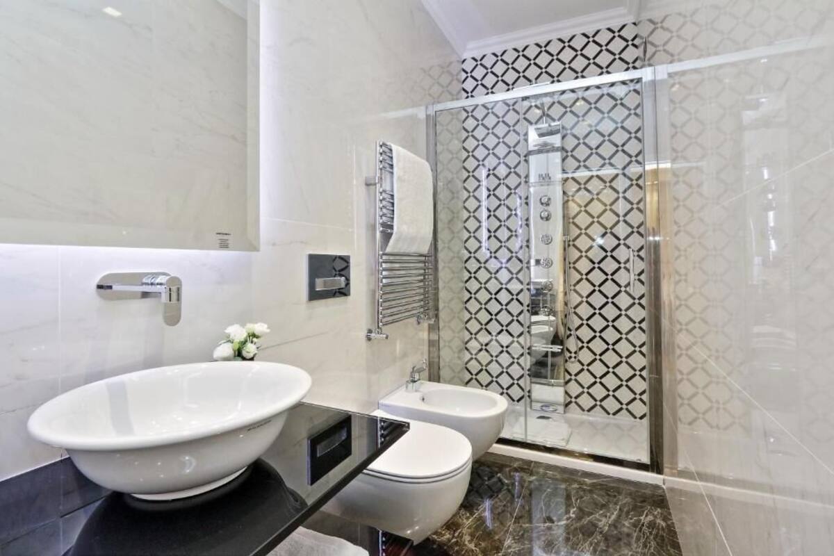 Un baño moderno con un lavamanos ovalado grande, un inodoro y una zona de ducha con paredes de vidrio.