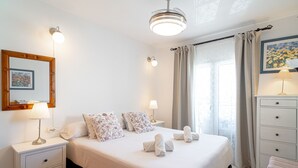 Un lit bien fait, avec des oreillers, une lampe de chevet et une table de chevet dotée d’un tiroir.