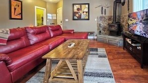Un salon avec un canapé en cuir rouge, une table basse en bois et une cheminée en pierre.