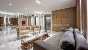 A modern hotel lobby with a spacious layout, a glass partition wall, and a seating area with sofas and a coffee table. - Super quiet, equipped and cozy Studio designed by travelers  (Edson Queiroz Fortaleza)