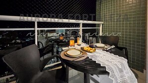 A dining area with a table set for two, featuring a lace tablecloth, wine glasses, and a bottle of wine. - Super quiet, equipped and cozy Studio designed by travelers  (Edson Queiroz Fortaleza)