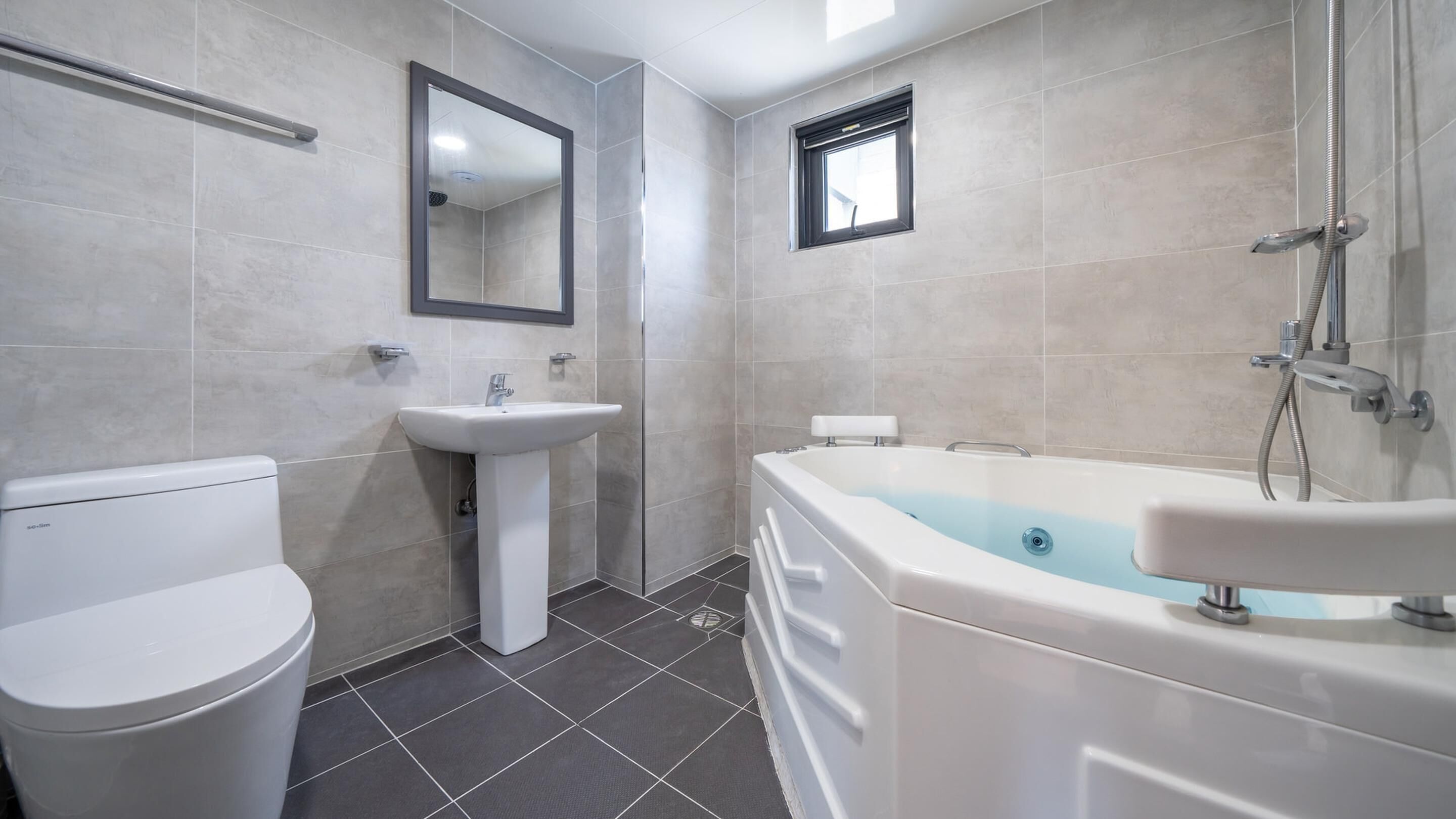 Een moderne badkamer met toilet, wastafel en bad.