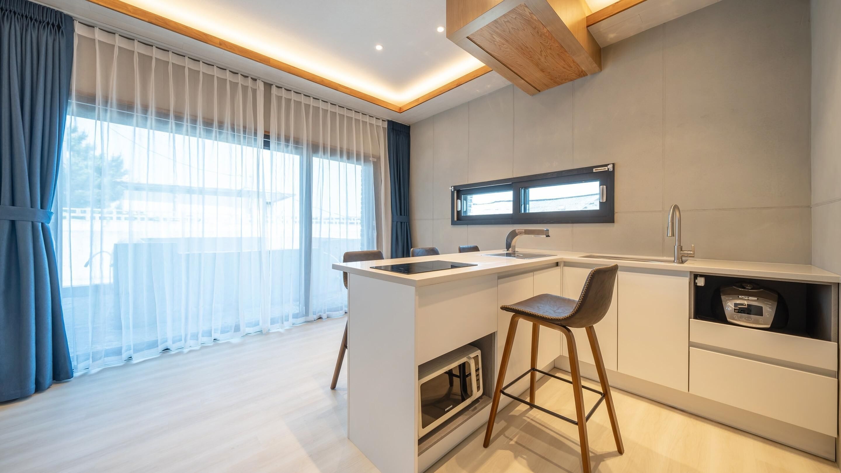 A modern kitchen with a built-in microwave, a sink, and bar stools.