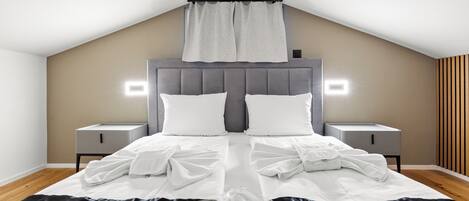 A neatly made bed with white linens, a grey headboard, and a wooden ceiling.