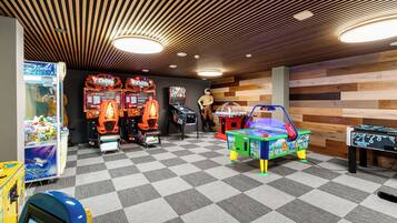 A room with a checkered floor, wooden ceiling, and various arcade games.