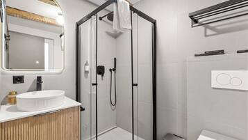 A modern bathroom with a glass-enclosed shower, a wooden vanity, a white sink, and a mirror with a wooden frame.
