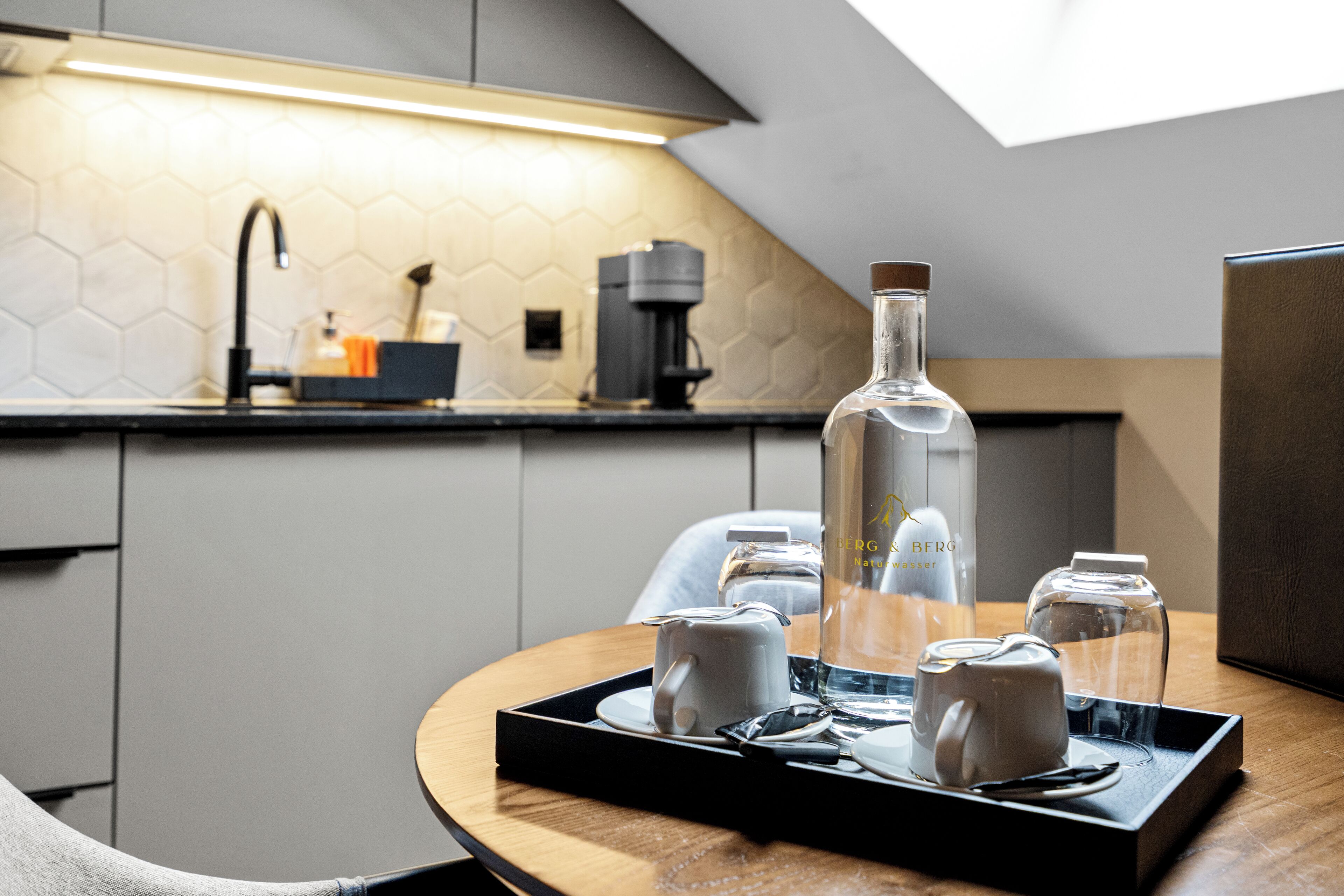 Eine moderne Küche mit Kaffeemaschine, Wasserspender und einer Flasche auf einem Tablett.