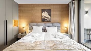 Une chambre d’hôtel moderne avec un grand lit, deux tables de chevet avec des lampes, une tête de lit et une œuvre d’art accrochée au mur.