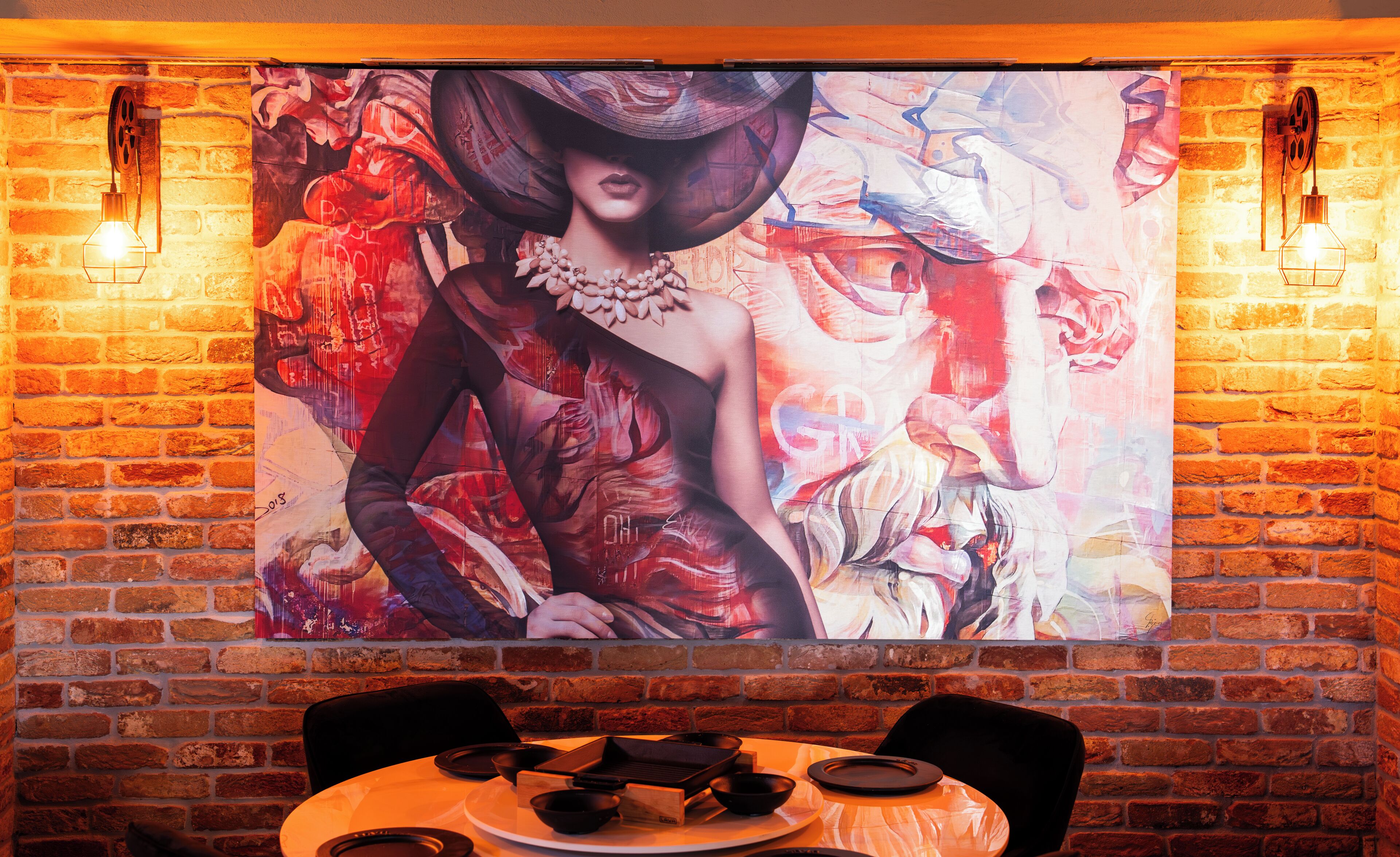 Um restaurante com parede de tijolos e uma grande pintura abstrata.