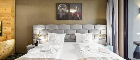 Una habitación de hotel con una cama grande, dos lámparas de noche, un cabecero con diseño acolchado y dos cuadros enmarcados en la pared.