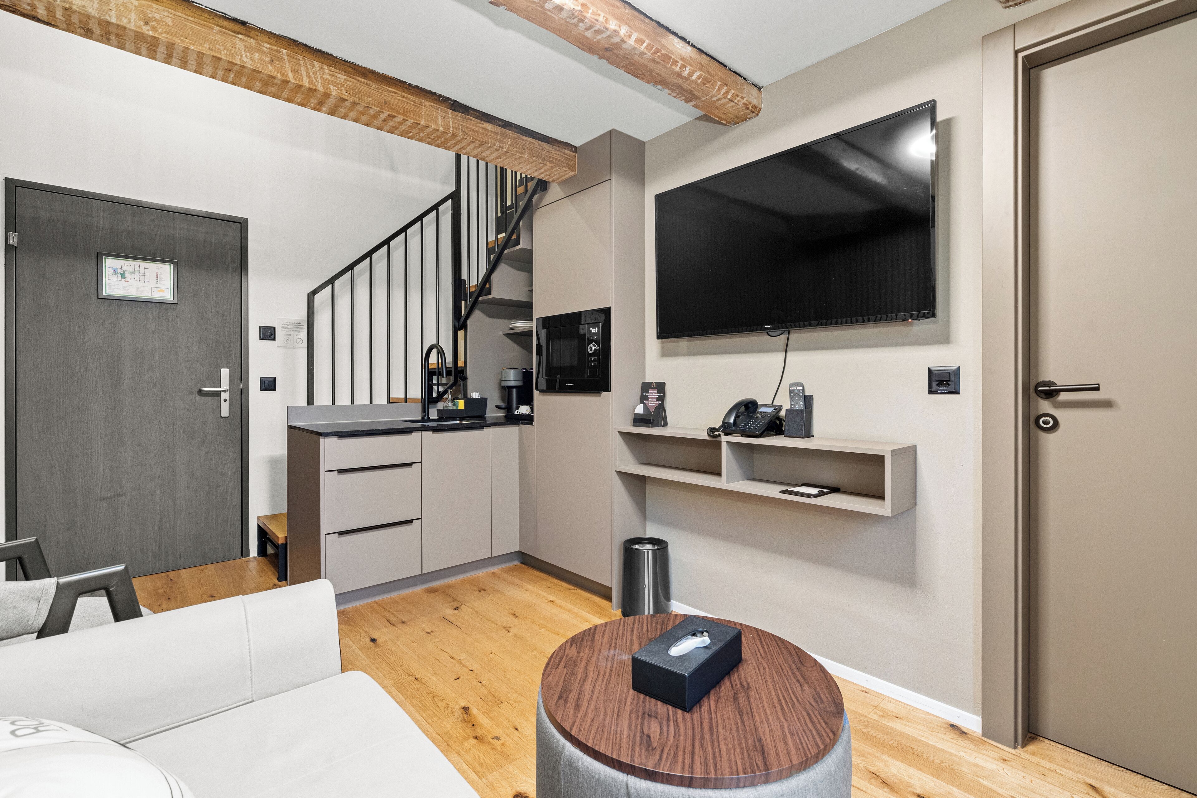 A modern kitchen with a microwave, coffee machine, and a flat-screen TV mounted on the wall.