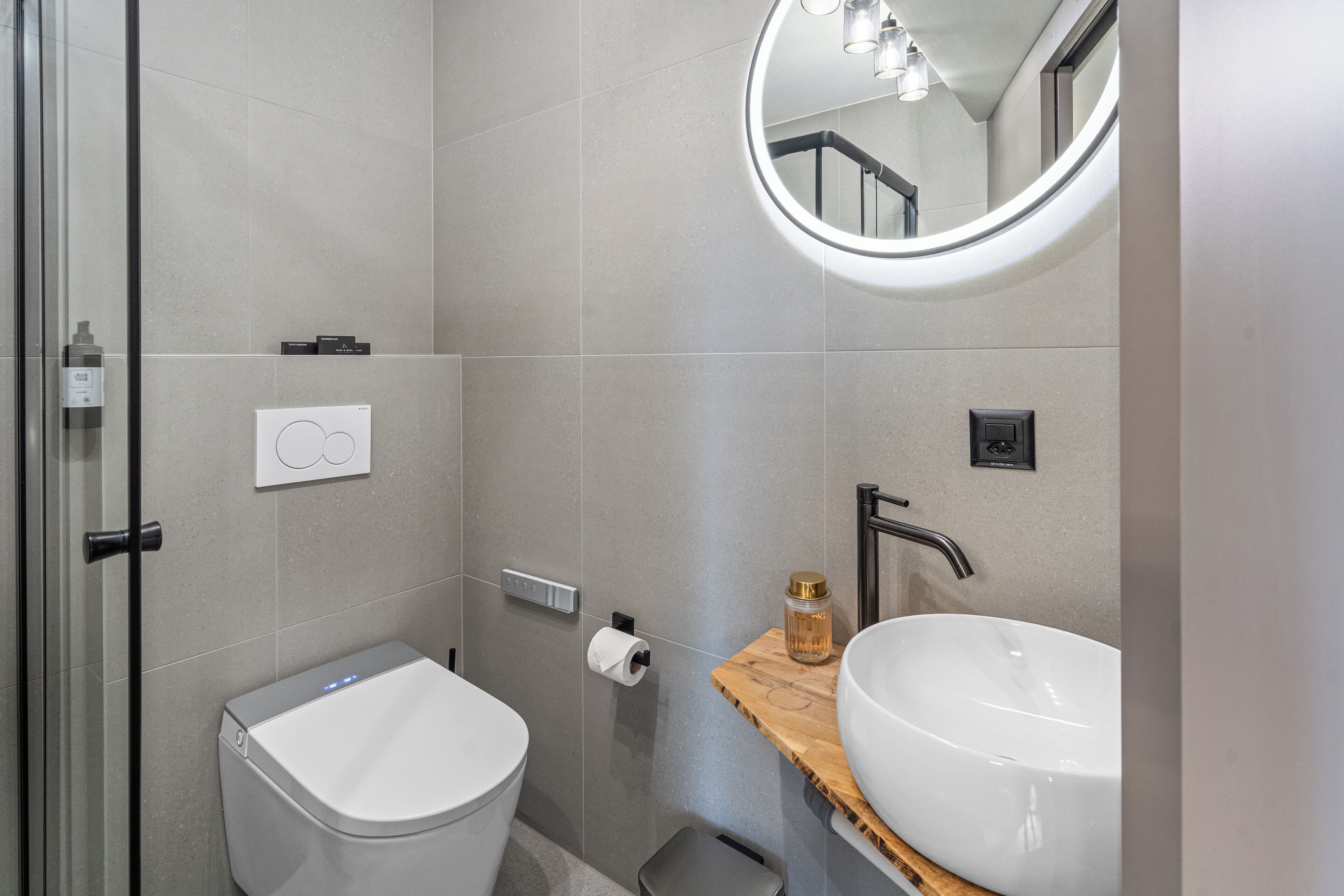 A modern bathroom with a toilet, sink, and mirror.
