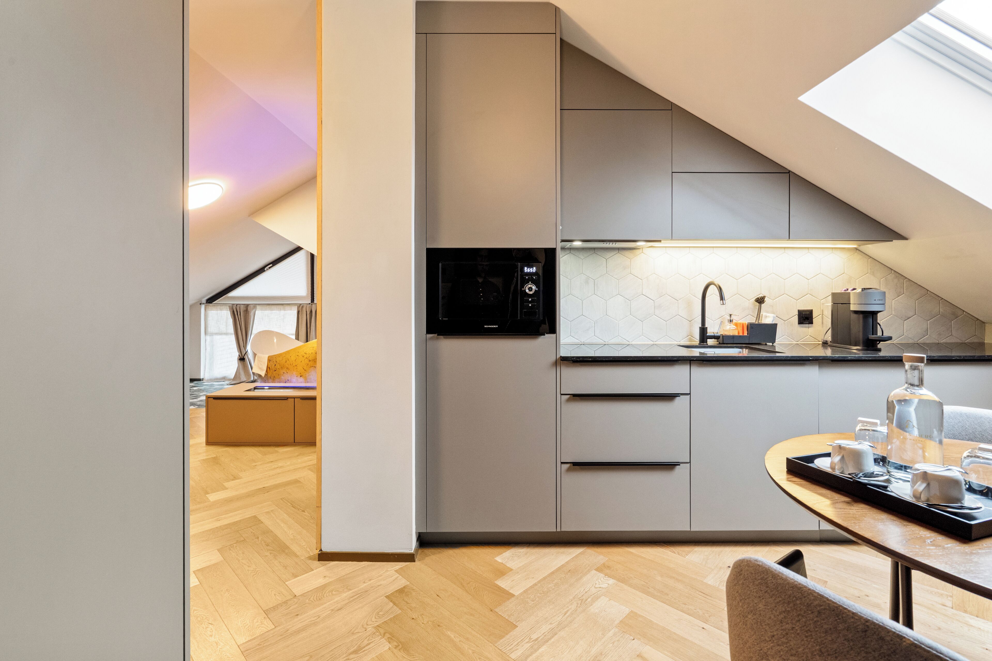 A modern kitchen with a microwave, coffee machine, and a dining area with a table set for two.