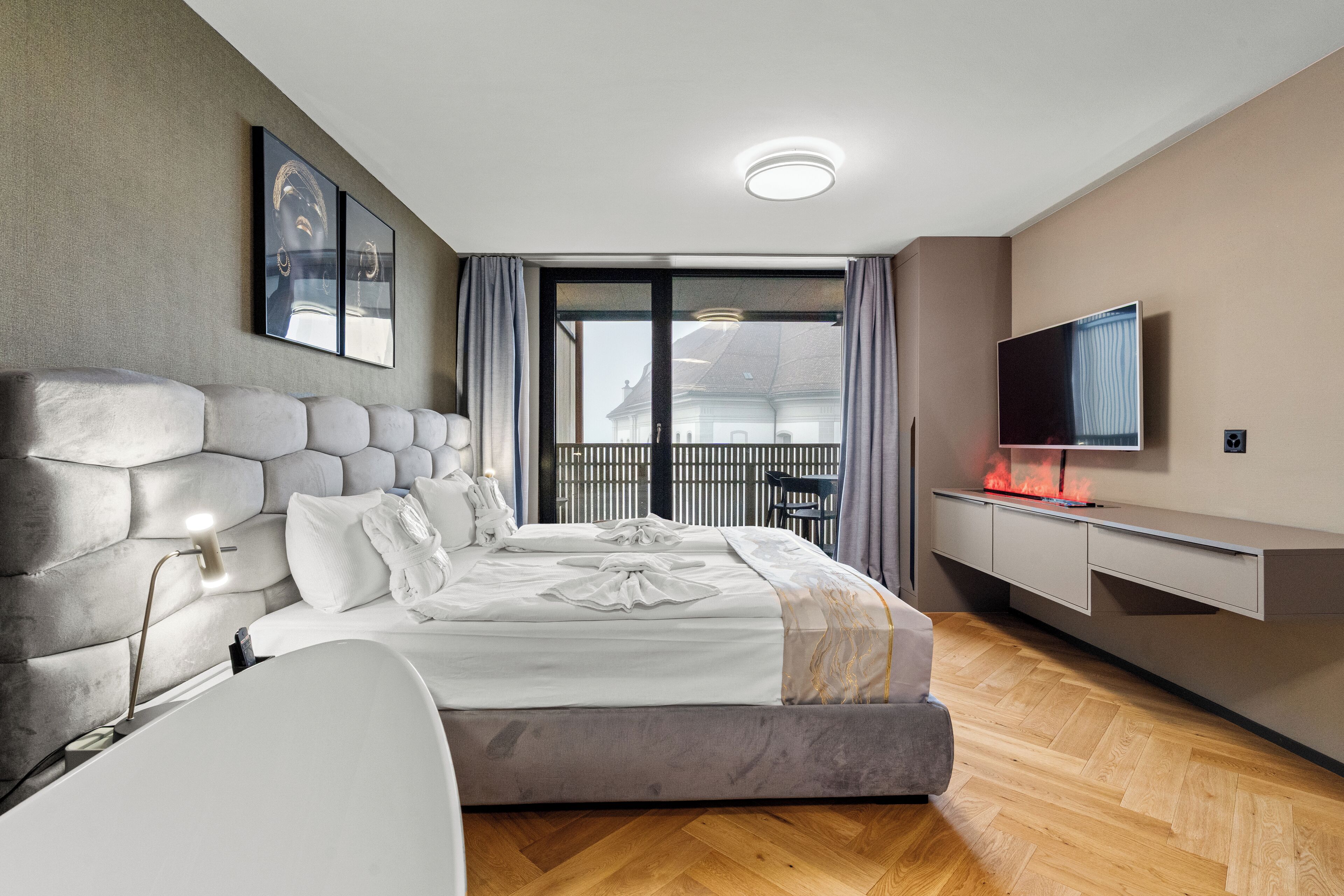 Un dormitorio moderno con una cama grande, un televisor de pantalla plana y un balcón con vistas.