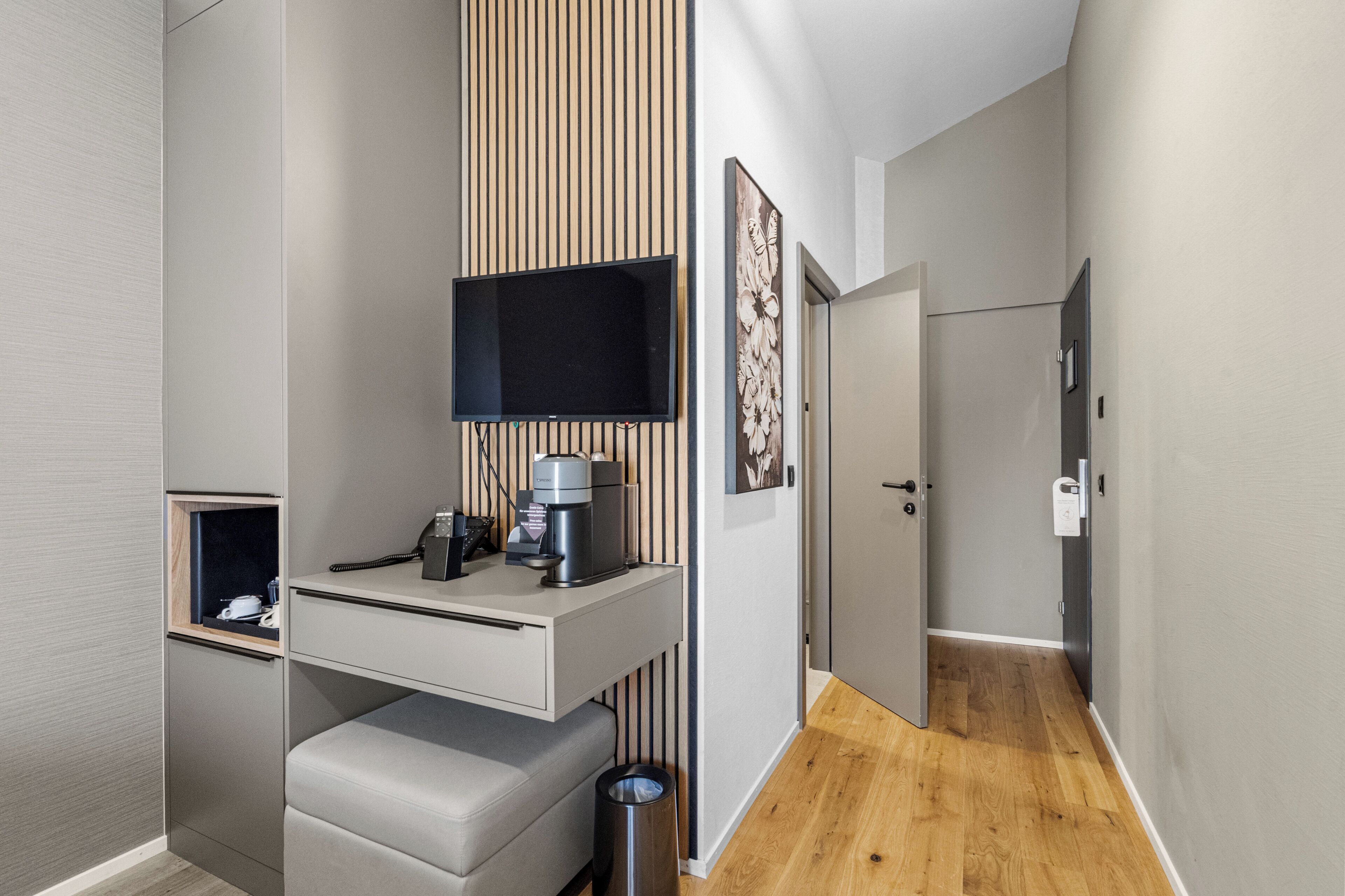 Een compacte hotelkamer met kitchenette, een flatscreen televisie, een klein zitgedeelte en een houten vloer.