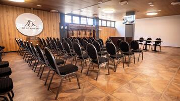 A conference room with rows of chairs, a wooden floor, and a logo on the wall.