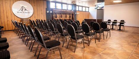 A conference room with rows of chairs, a wooden floor, and a logo on the wall.