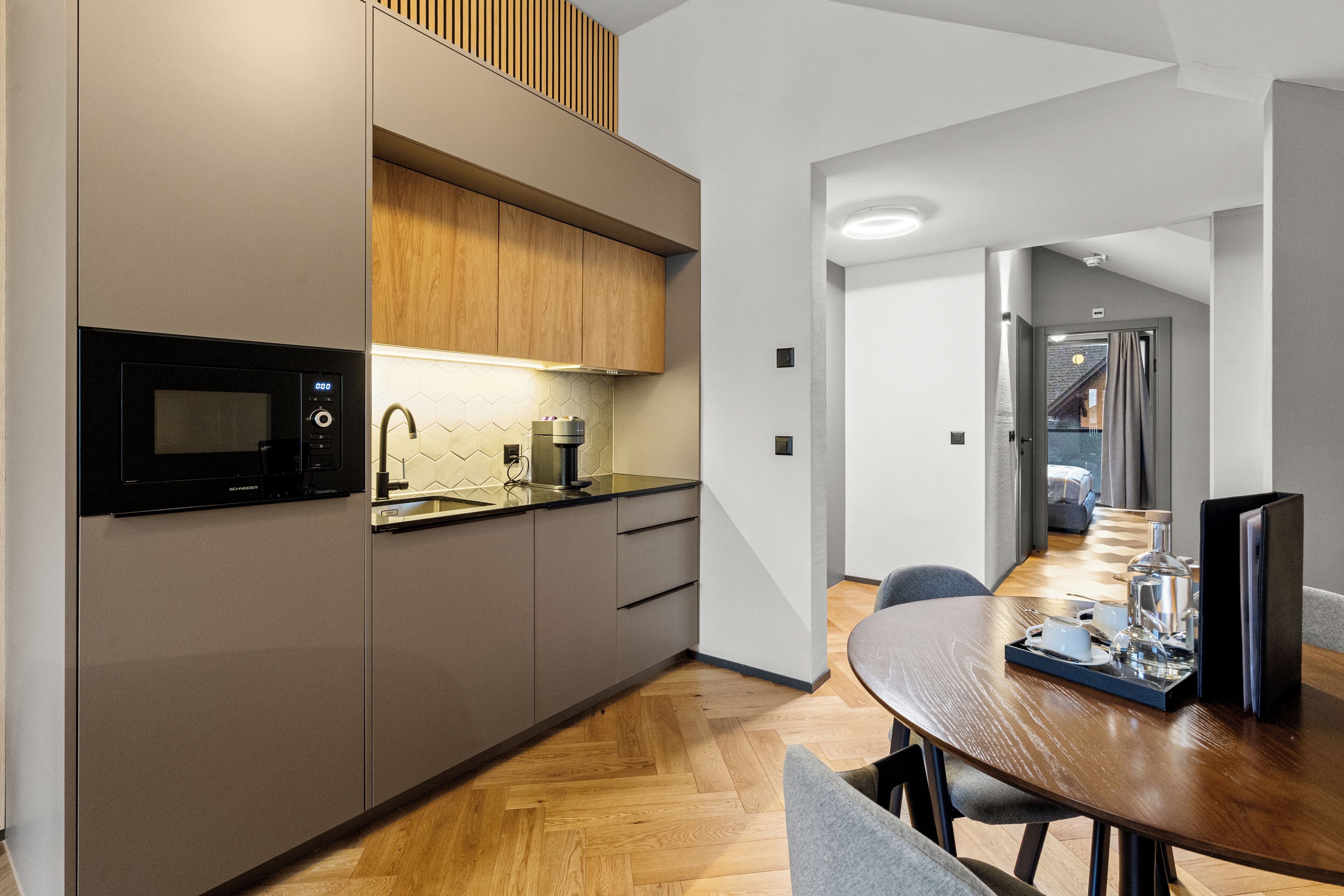 Una cocina moderna con microondas, armarios de madera y un comedor con una mesa dispuesta para dos personas.