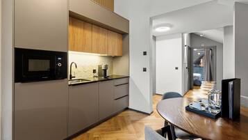 Una cocina moderna con microondas, armarios de madera y un comedor con una mesa dispuesta para dos personas.