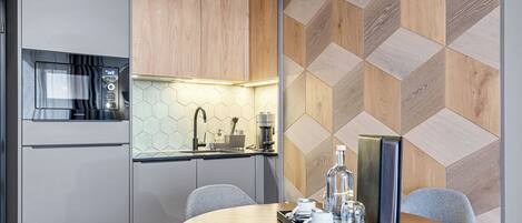 A modern kitchen with a microwave, coffee maker, and a hexagonal backsplash.