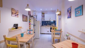 A compact kitchen with white cabinets, a dining table, and chairs. There are hanging lights and a refrigerator. - Flegreo bed and breakfast (Naples)
