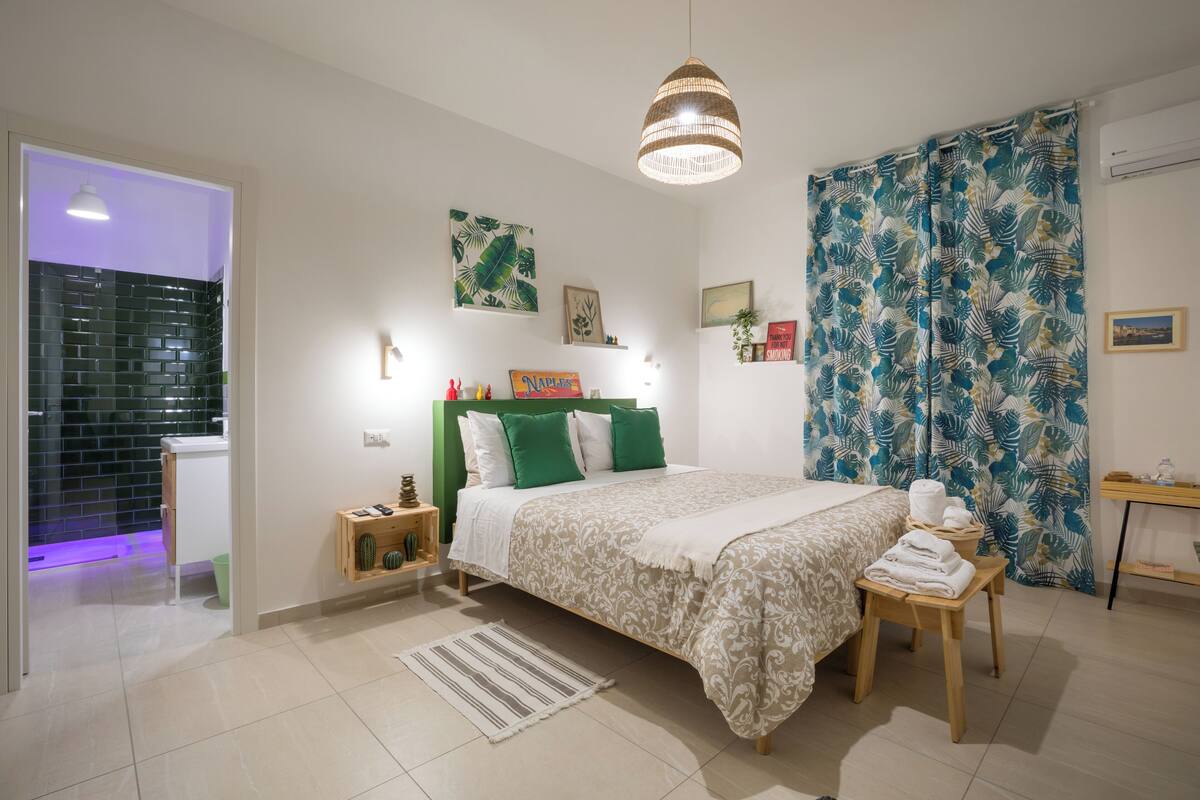 Ein modernes Schlafzimmer mit einem Bett, Nachttischen, einer Pendelleuchte und einer Dusche.