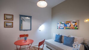A room with a white sofa, red chairs, a small table, a painting, and a ceiling light. - Flegreo bed and breakfast (Naples)