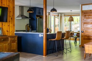 A modern kitchen with wooden accents, a central island with bar stools, and a dining area with natural light.
