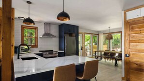 Una cocina moderna con una isla central, armarios de madera, un refrigerador de acero inoxidable e iluminación colgante.