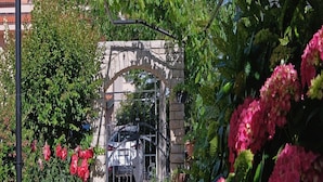 A gated entrance with a stone archway, surrounded by lush greenery and flowering plants. - Penthouse Stella (Pula)