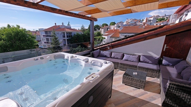 A rooftop terrace with a hot tub, outdoor seating, and a view of the cityscape. - Penthouse Stella (Pula)
