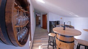 A modern kitchen with wooden barrel accents, a round bar table, and a wine rack. - Penthouse Stella (Pula)
