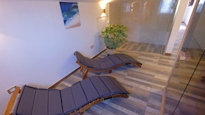 A room with two wooden lounge chairs with dark cushions, a potted plant, and a large mirror reflecting the room. - Penthouse Stella (Pula)