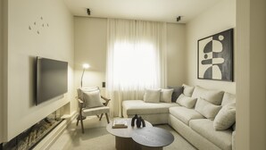 Un salon moderne avec un téléviseur à écran plat, un canapé, un fauteuil et une table basse.